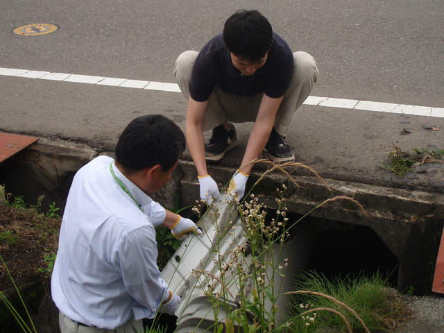 水路のゴミを拾う職員